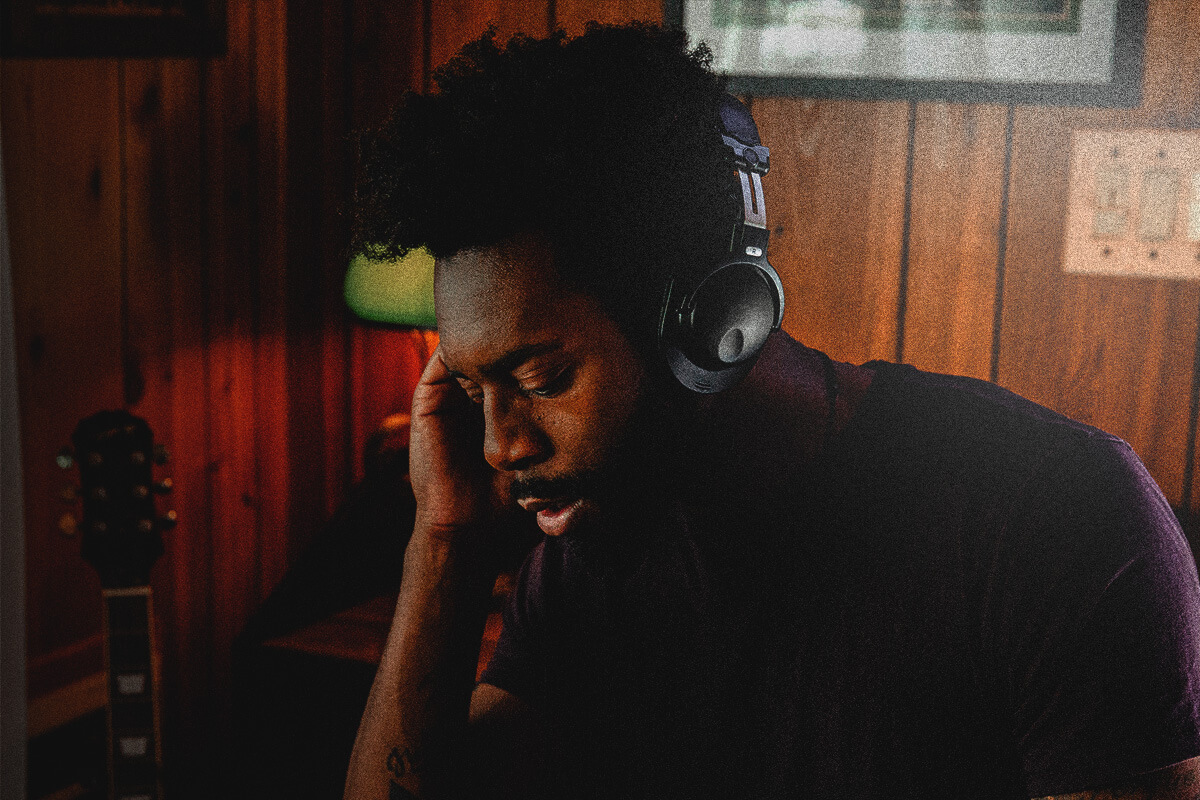 In the studio, a curly-haired DJ with a headset operates the mixer